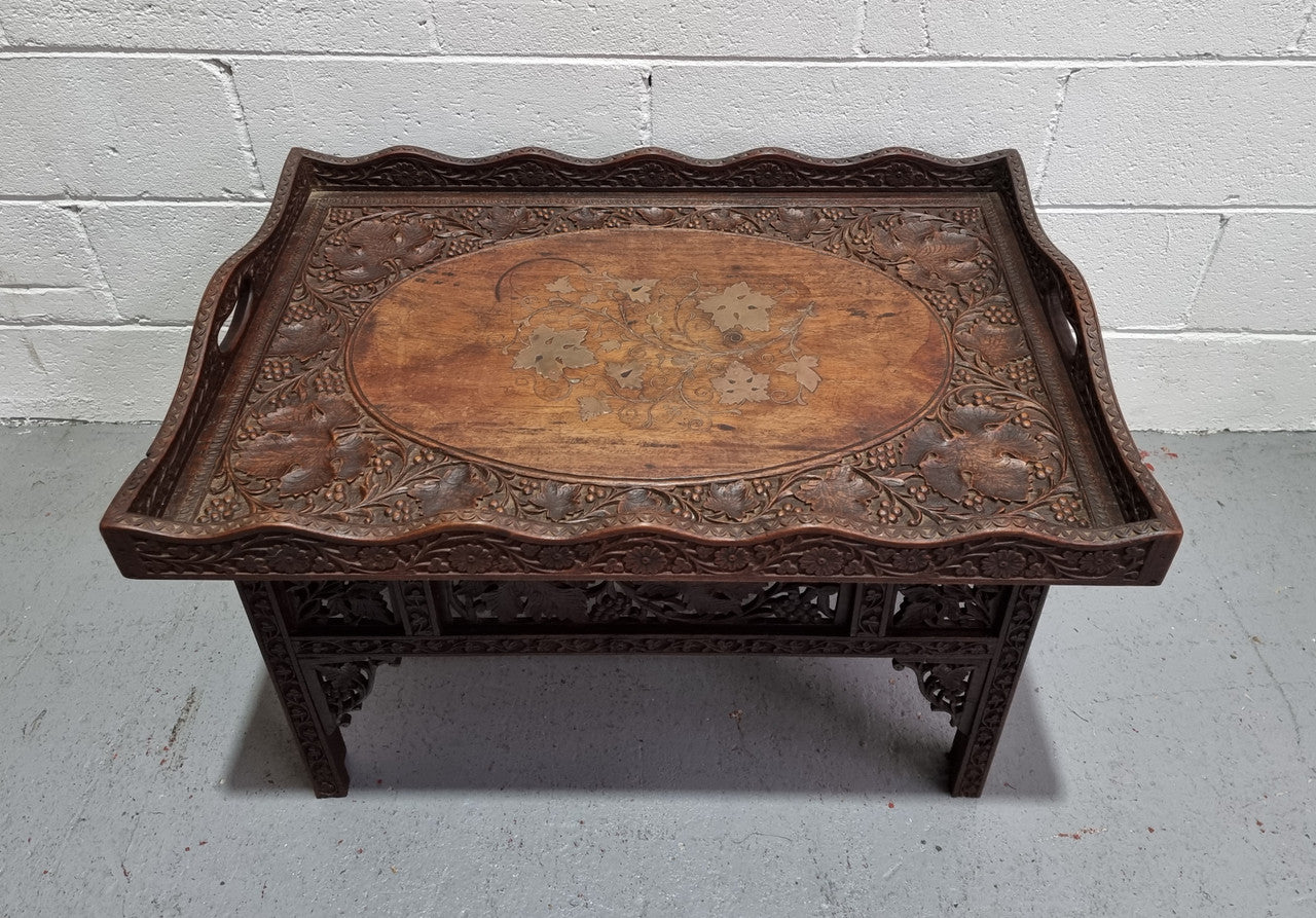Anglo Indian folding occasional table with lift-up tray top. The tray has brass inlay and ornate carvings. The bottom of the table folds down and it is in good original condition.