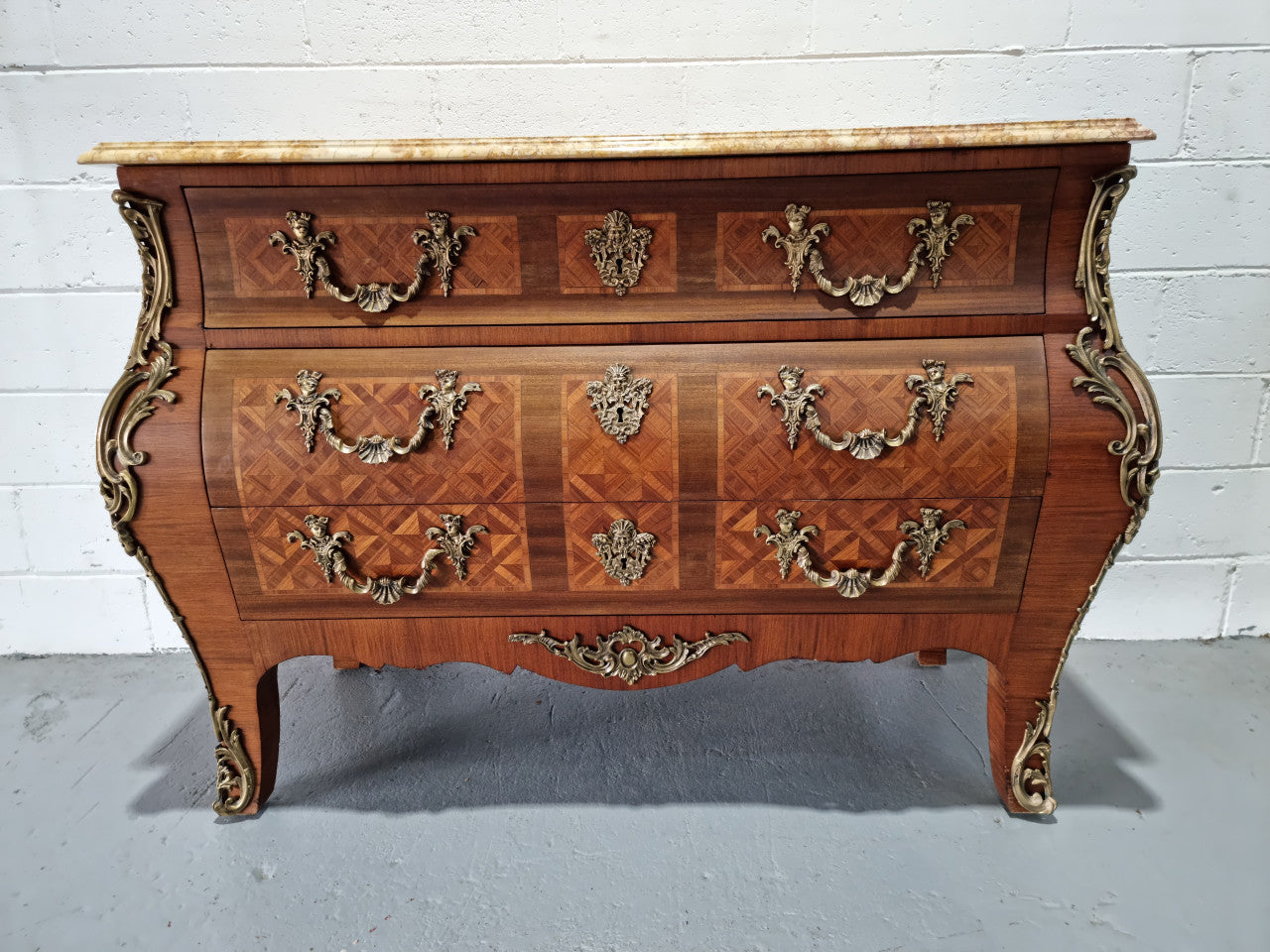 A beautifully inlaid parquetry three drawer commode with a lovely marble top, and decorative ormolu mounts. In good original detailed condition. Circa 1930