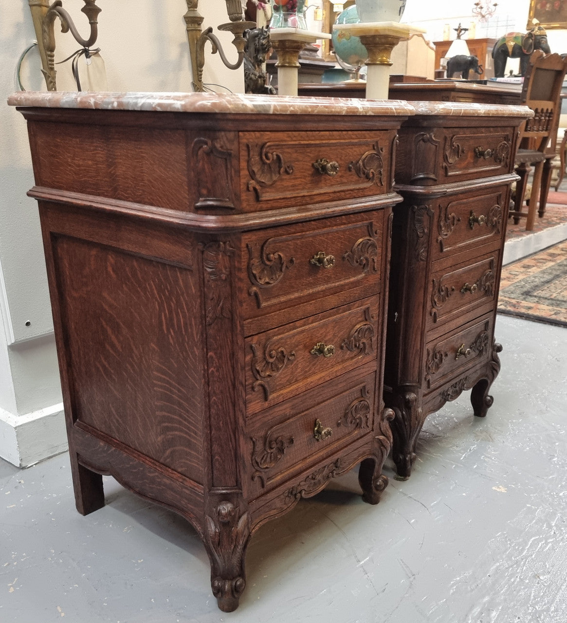 A pair of hard to find French Oak Louis XV style four drawer marble topped bedsides with attractive carvings. They are in good original detailed condition and have been sourced from France.