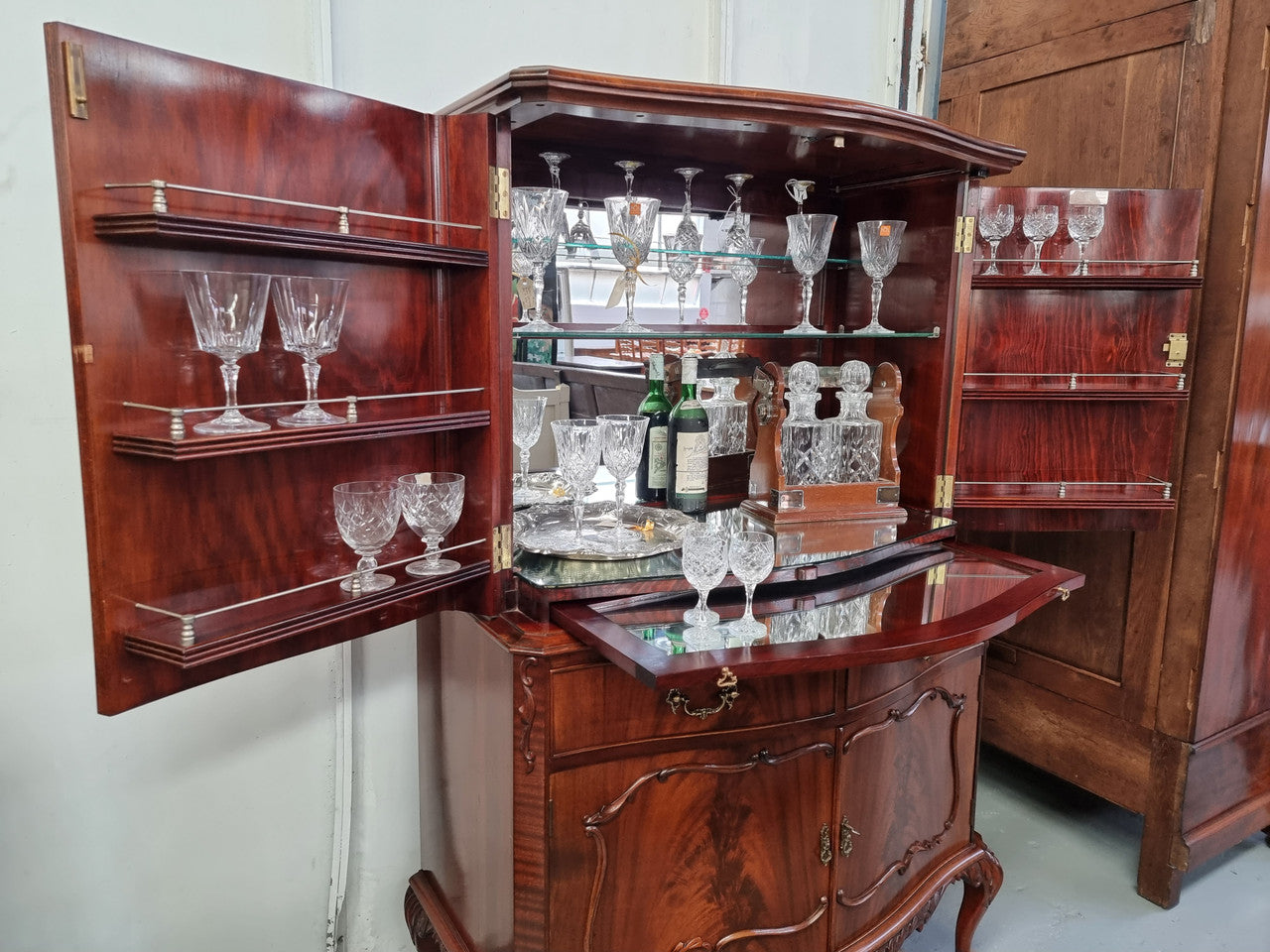 1950’s Chippendale Style Flame Mahogany Four door Bar. The top section has glass shelves and a mirrored pull out tray for storing glasses, decanters & serving etc. It also has a silver presentation plaque to the Mayor of Hawthorn 1958. The bottom section is for storage bottles etc. A stunning and practical piece.