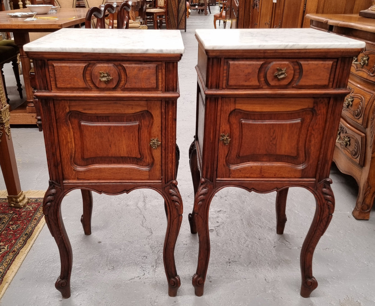 Elegant French Louis XV style pair of carved Oak white marble top bedsides. They are in good original condition and they have been detailed to a high standard. They have been sourced from France.