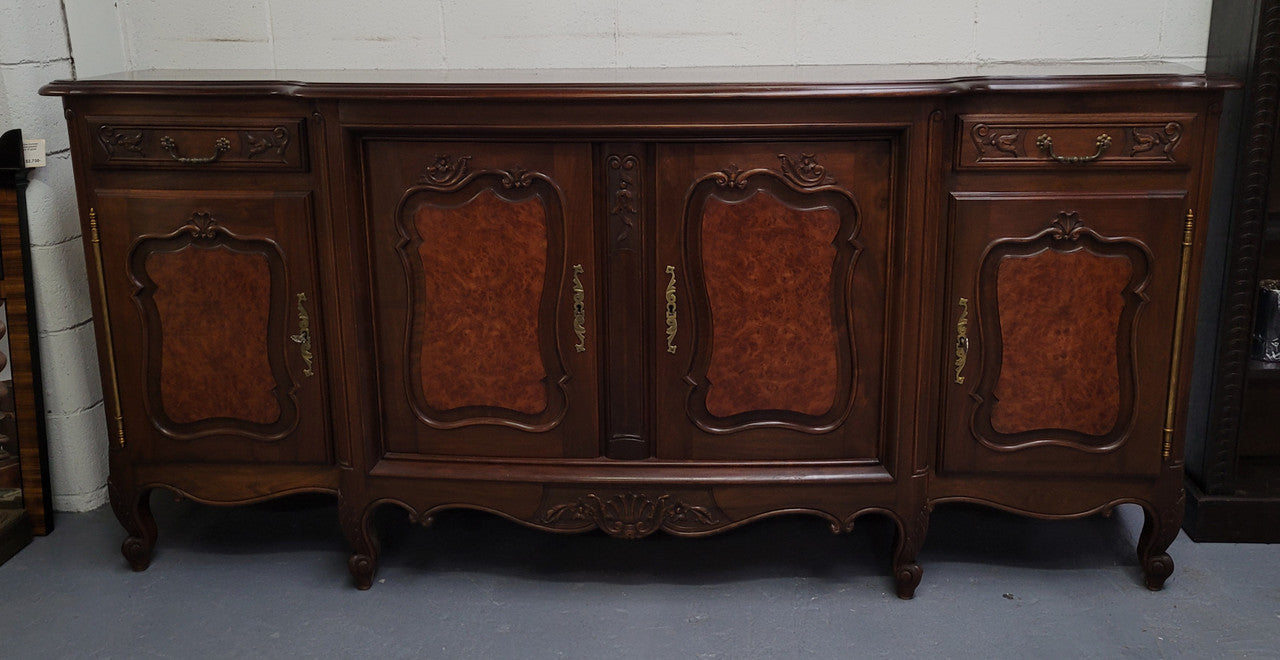 Fabulous Louis XV style French Walnut and Burr Walnut four door sideboard. Each door panel has beautiful Burr Walnut panels and open up to an adjustable shelf. Beautiful handles and two drawers for added storage. In good original detailed condition.