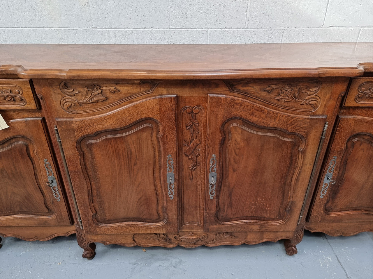 Parquetry top French oak Louis XV style sideboard with two draws and four cupboards. In good original detailed condition.