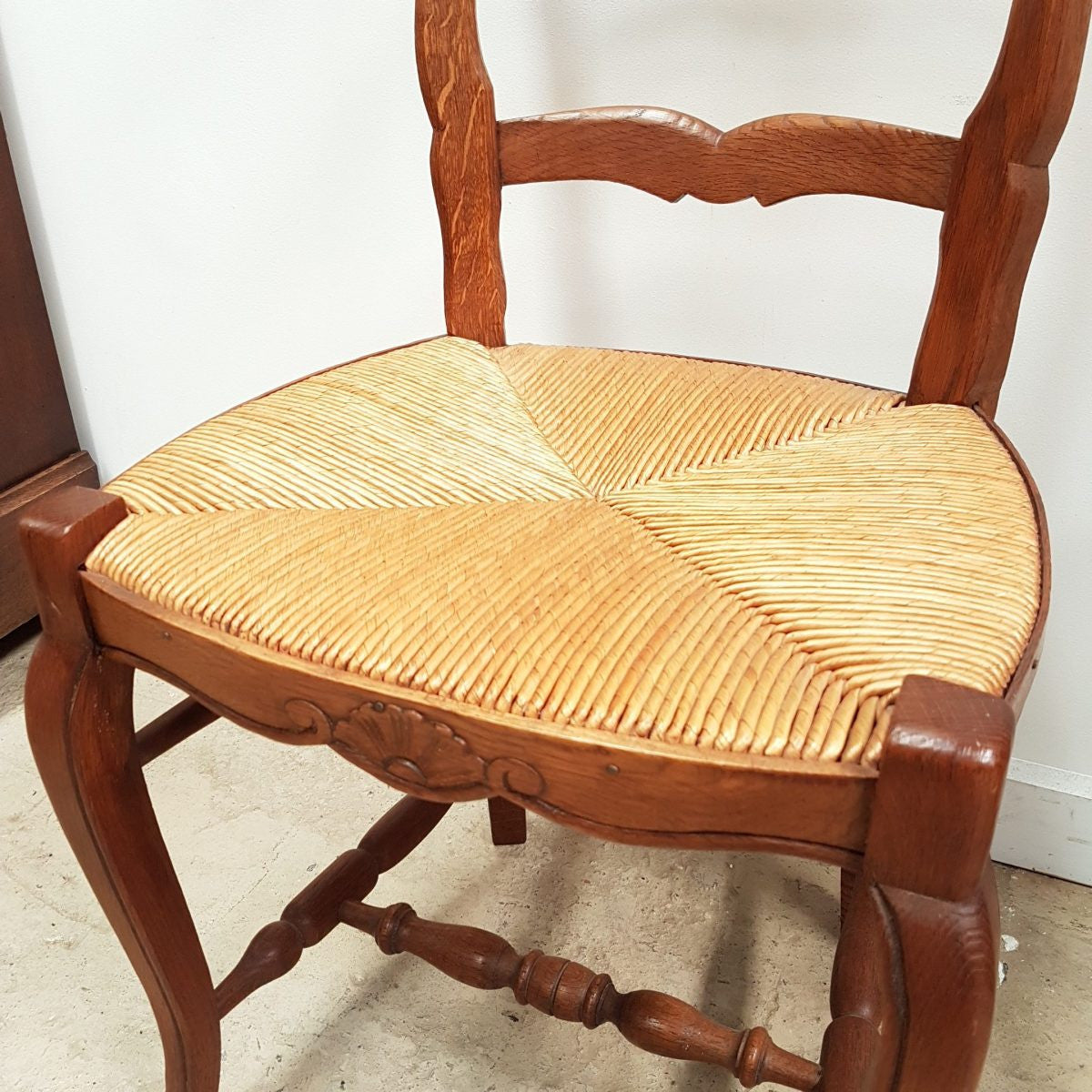 A set of six French Louis XV style, ladder back oak chairs. With finely carved detail and rush seat. In great original condition. Chairs are comfortable and sturdy for everyday use.