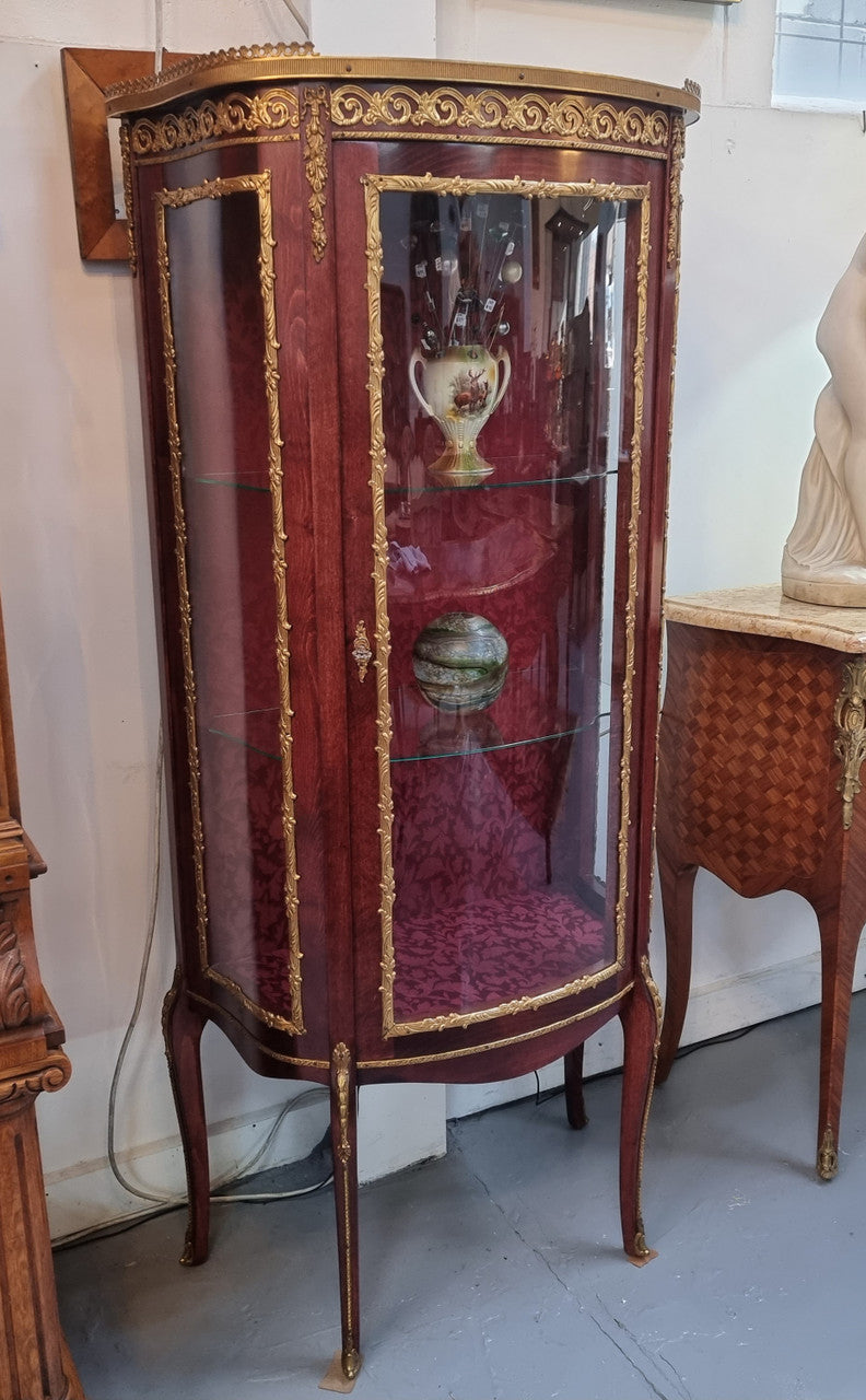 French Mahogany two shelf vitrine with curved glass and brass mounts. It has a lovely frabic interior and two glass shelves. In good original detailed condition.