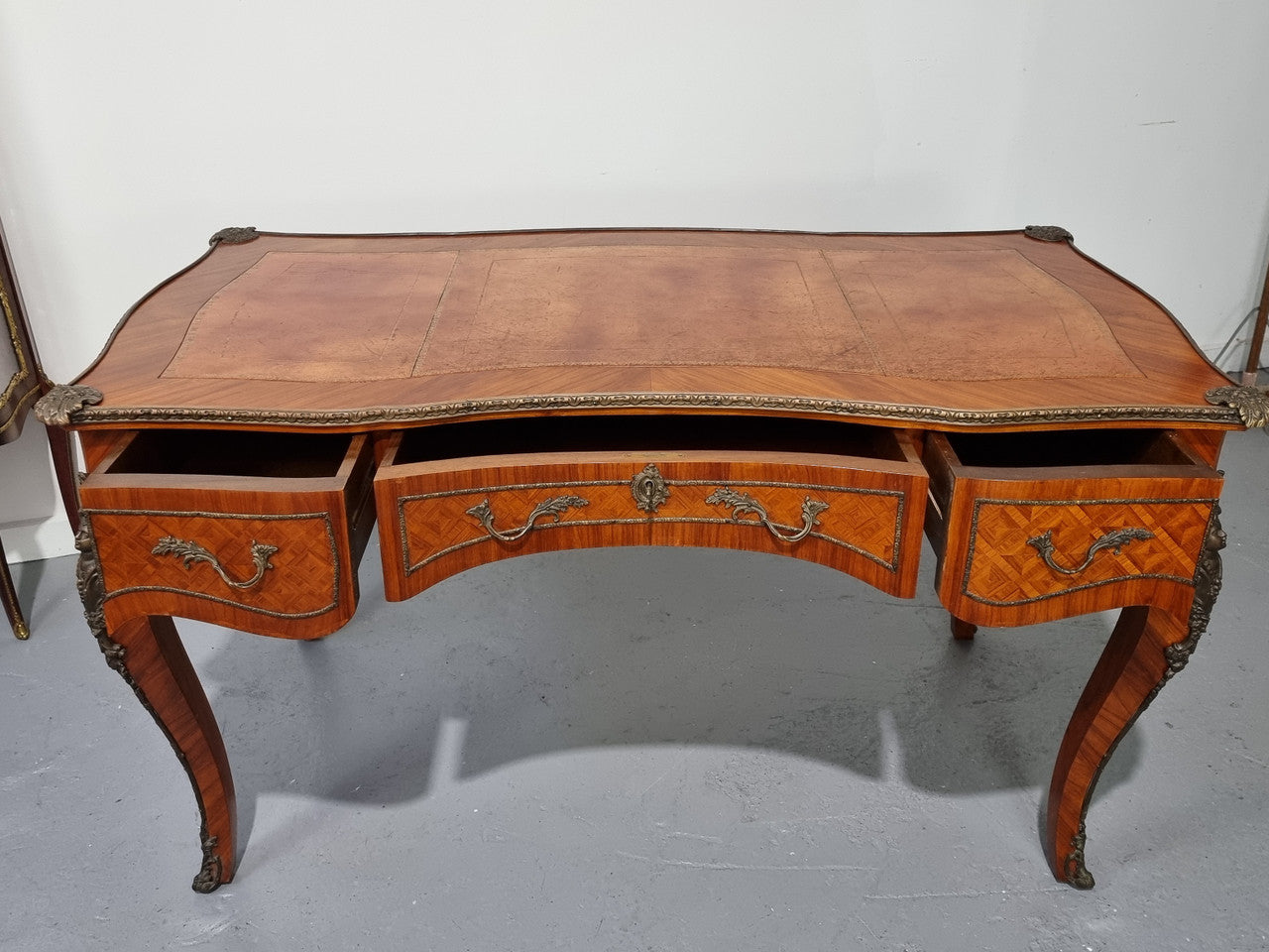 An impressive French kingwood and ormolu mounted bureau plat. It has a brown tooled leather writing surface, three decorated frieze drawers to the shaped apron with foliate swing handles and well cast figural mounts. Beautiful cabriole legs with decorative ormolu mounts and trims throughout. In good original detailed condition.