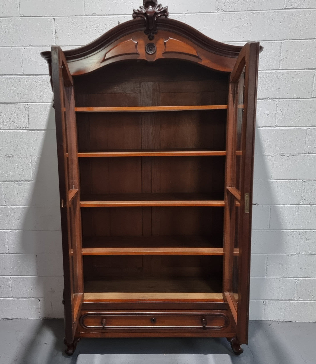 Antique Mahogany two door Biedermeier style bookcase with four fully adjustable shelves and a drawer at the bottom. The two wooden finials at the top are easily removed for a different look of desired. In good original detailed condition.