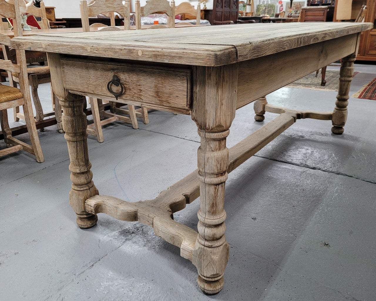 French stripped Oak pedestal stretcher base Farmhouse table with two drawers on either side of table. Features raw wood that could be used as is for a distressed look, or finished and waxed for a more refined look.