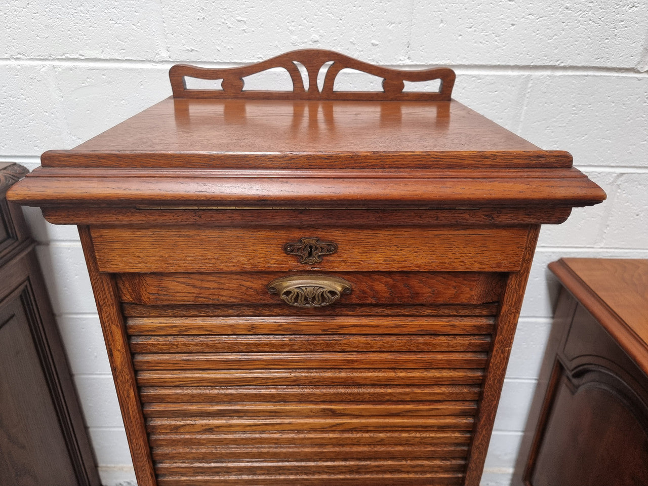 Antique Edwardian roll top Tambour file cabinet desk. This practical antique tambour front filing cabinet dates around 1900 in the Edwardian period and is constructed from Oak. This antique cabinet has an adjustable writing slope, above a tambour front with key and working lock. It has been sourced locally and is in good original detailed condition.