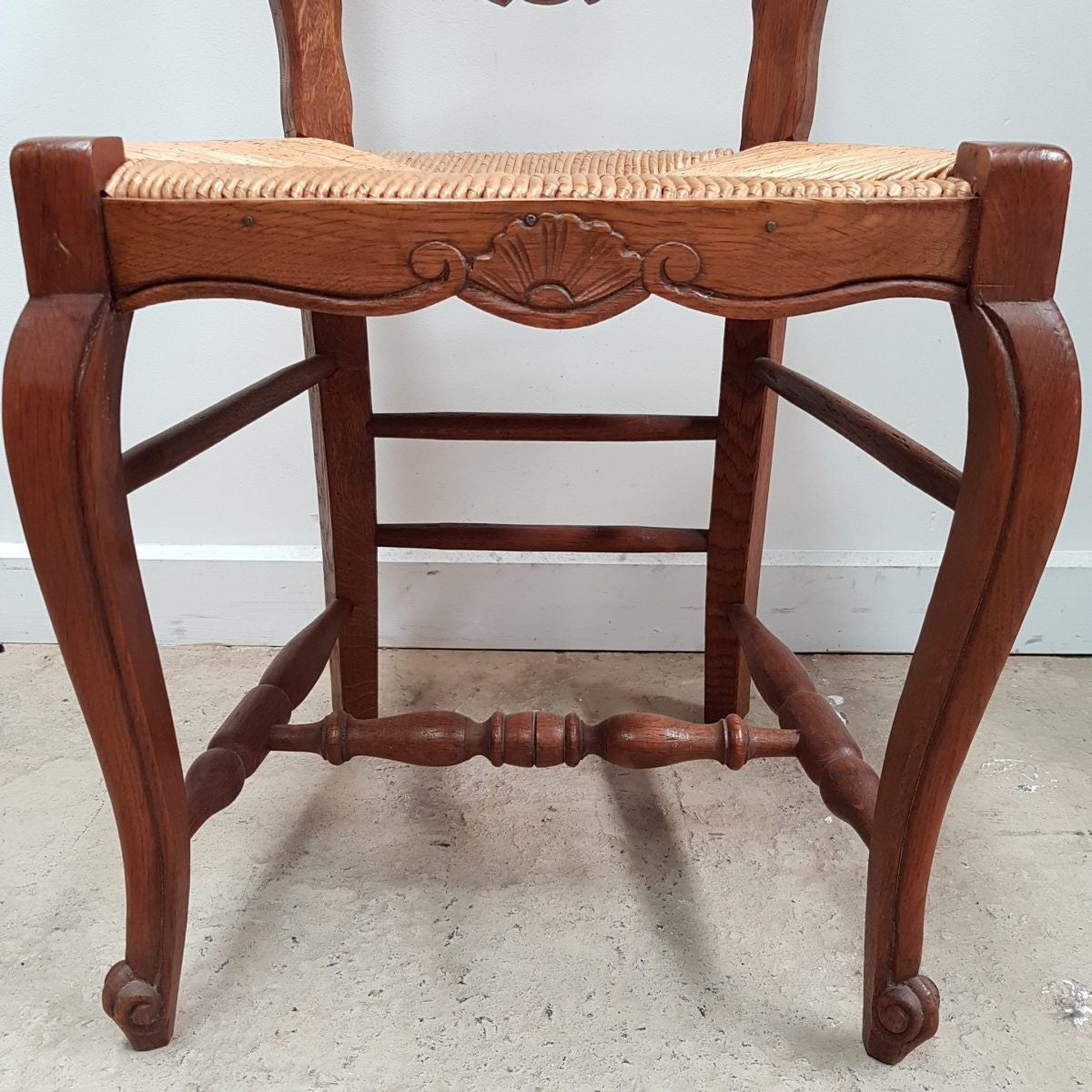 A set of six French Louis XV style, ladder back oak chairs. With finely carved detail and rush seat. In great original condition. Chairs are comfortable and sturdy for everyday use.