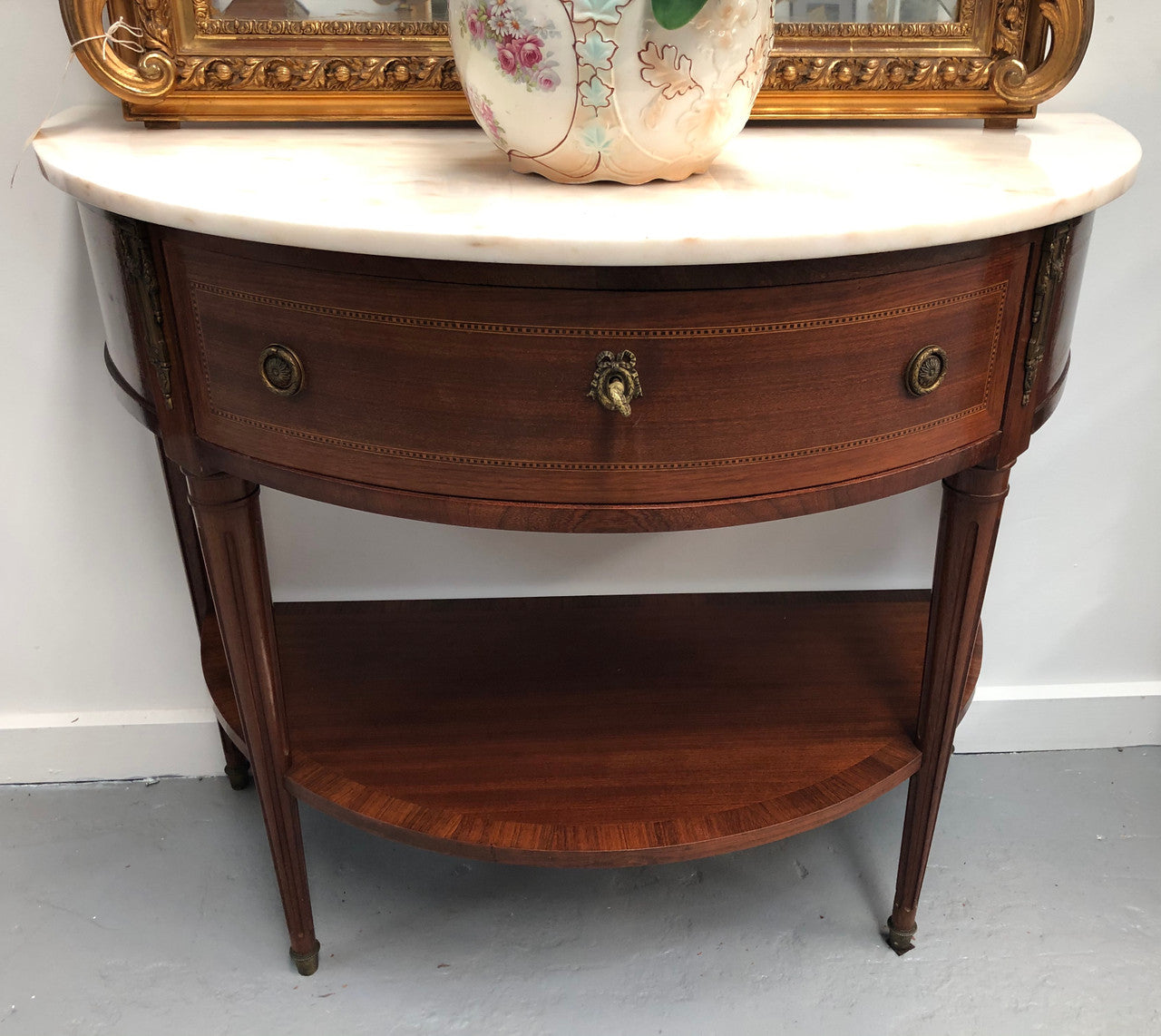 French marble top half round console table. It has beautiful marquetry inlay and ormolu mounts with a single drawer. In good original condition.