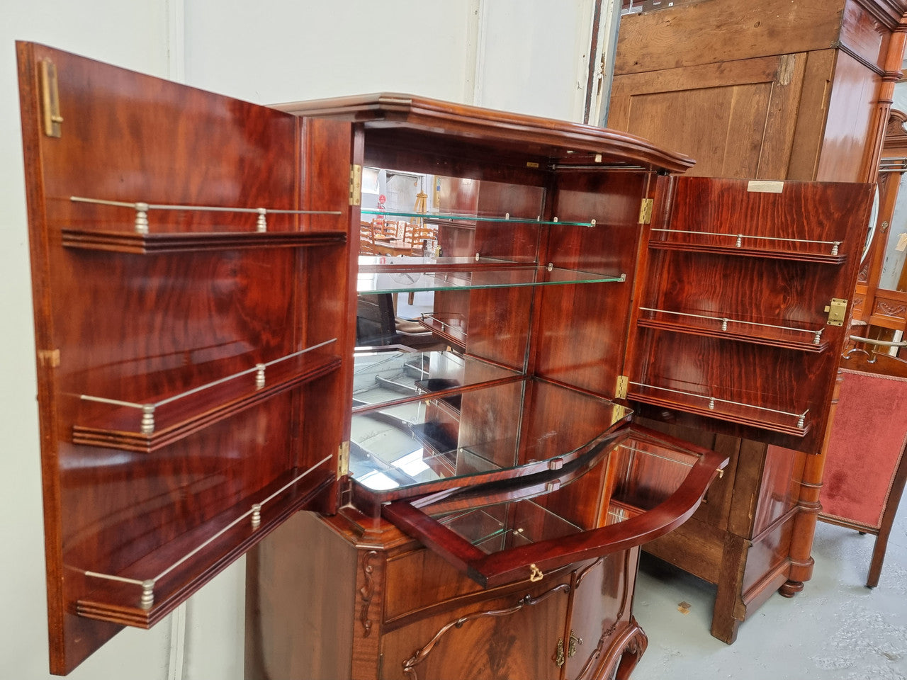 1950’s Chippendale Style Flame Mahogany Four door Bar. The top section has glass shelves and a mirrored pull out tray for storing glasses, decanters & serving etc. It also has a silver presentation plaque to the Mayor of Hawthorn 1958. The bottom section is for storage bottles etc. A stunning and practical piece.