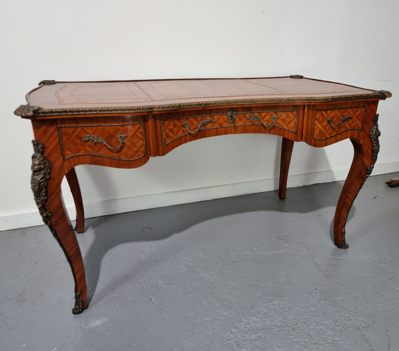 An impressive French kingwood and ormolu mounted bureau plat. It has a brown tooled leather writing surface, three decorated frieze drawers to the shaped apron with foliate swing handles and well cast figural mounts. Beautiful cabriole legs with decorative ormolu mounts and trims throughout. In good original detailed condition.