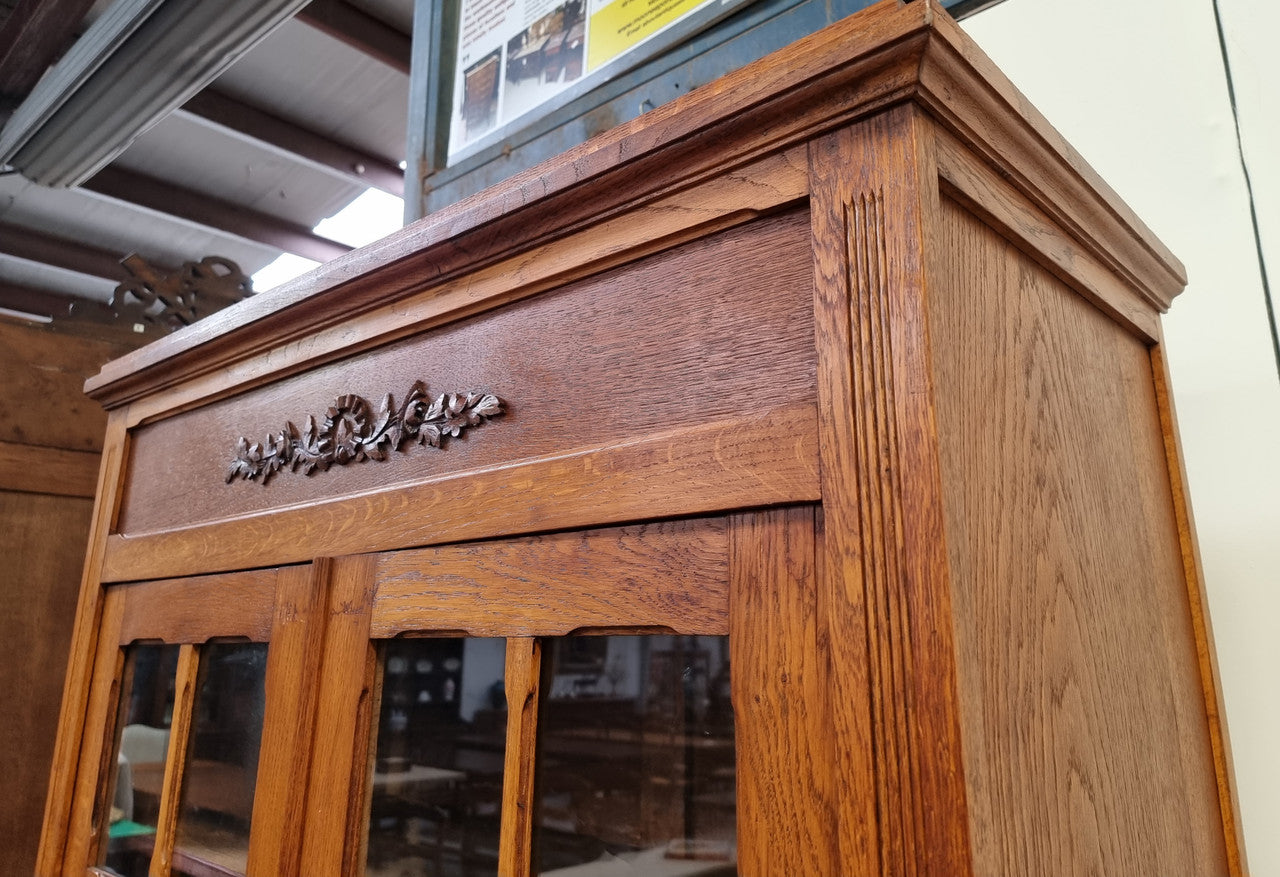 French light Oak two door bookcase with four adjustable shelves. It has beautiful decorative carving and is in good original detailed condition.