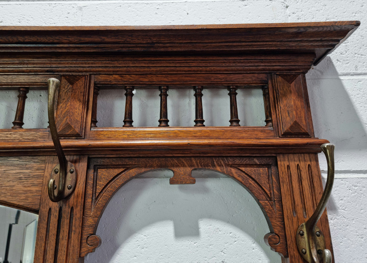 Grand Henry 2nd Style French Oak hall stand with 12 hanging hooks. Also has one cupboard and drawer for storage along with a mirror and two areas either side for umbrellas and walking sticks. In good original detailed condition.