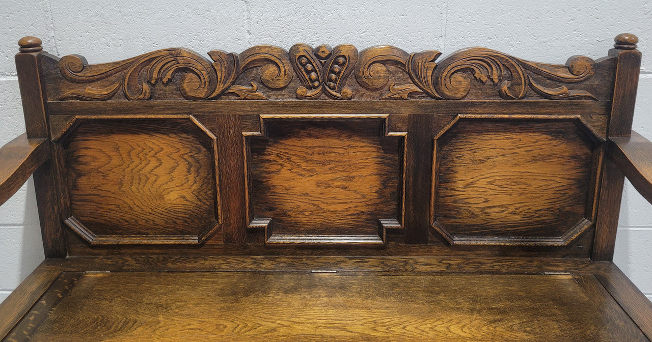 English Oak Tudor style hall seat with lift up top and a storage compartment underneath. It is in good original detailed condition with its original finish.