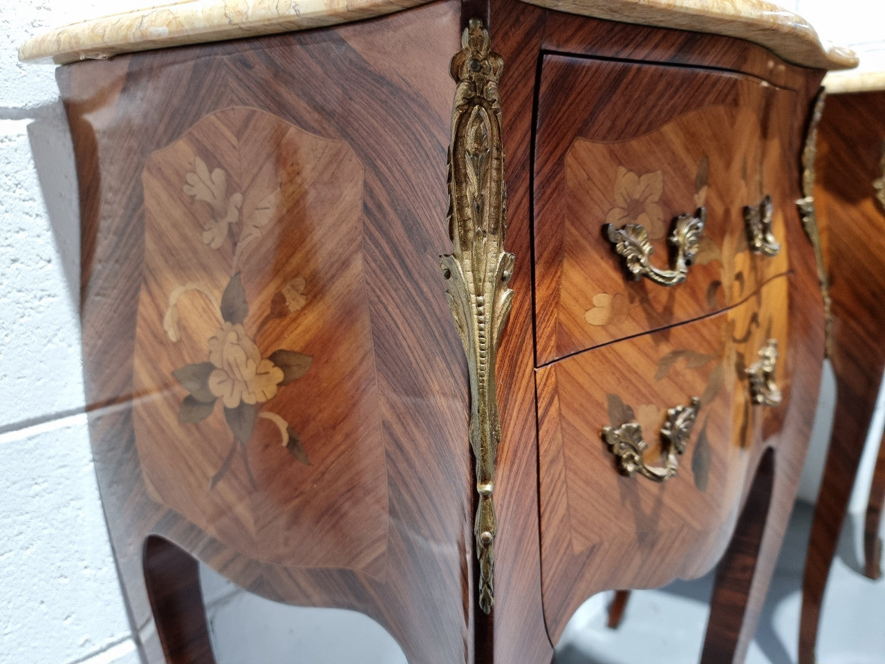 Pair of French bombe shaped commode style marquetry inlaid Kingwood bedside cabinets with marble tops and gilt brass mounts. Circa 1930 in good original detailed condition.