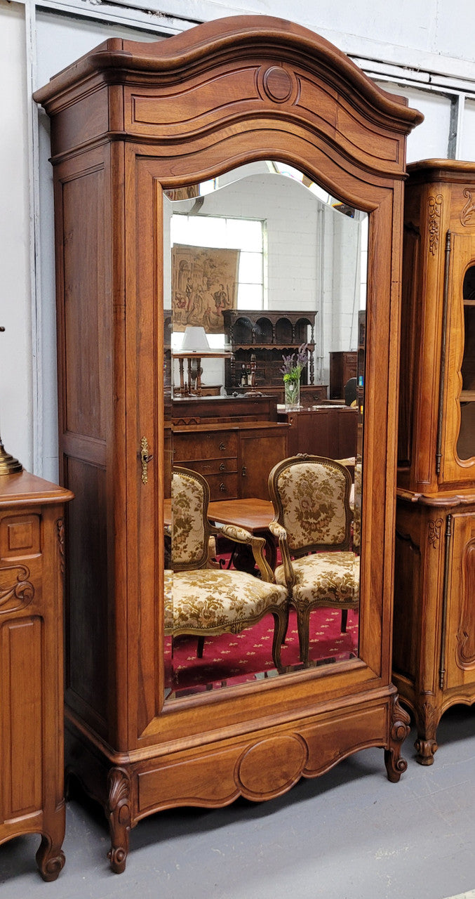 French Louis XV style Walnut armoire with single bevelled mirrored door. It has four adjustable shelves and a hidden exterior drawer at the bottom. It has been sourced from France and is in good original detailed condition.