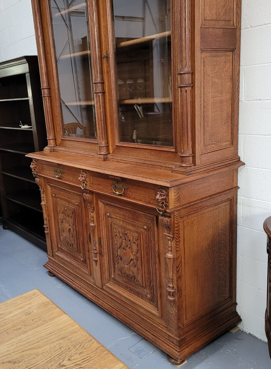 Amazing French 19th Century Oak two-door bookcase. Amazing detailed carvings throughout and plenty of storage space with three adjustable shelves at the top, two drawers, and a further shelf at the bottom. Also has two pull out reading slides giving you a large area to view your books on. In very good original detailed condition.