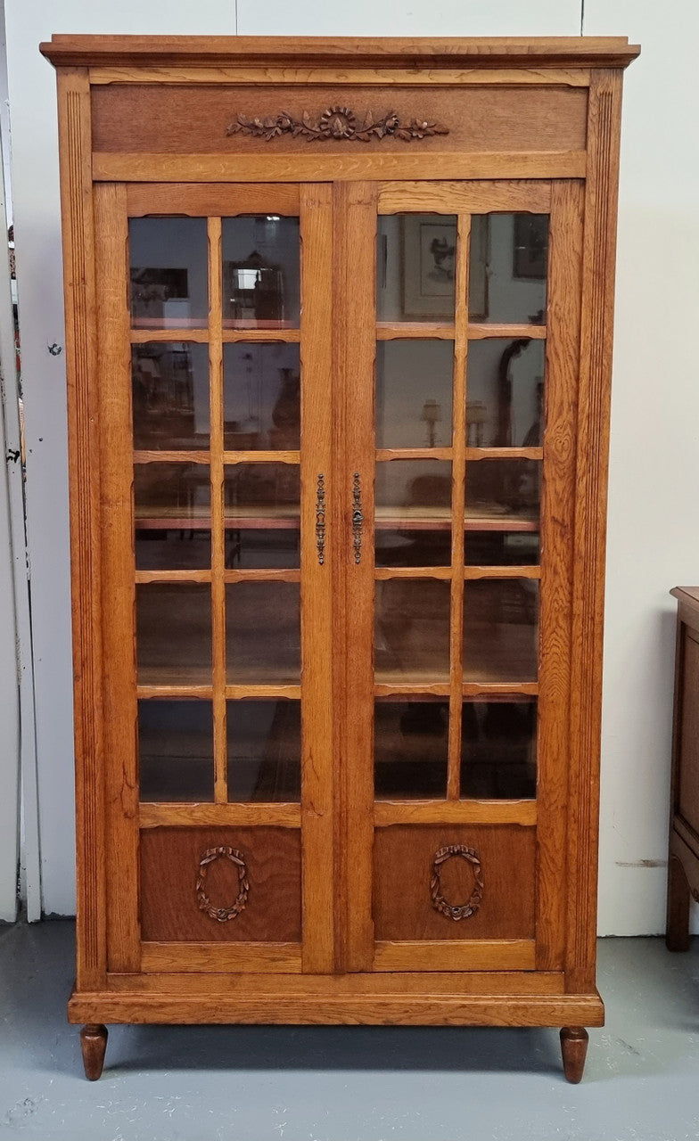 French light Oak two door bookcase with four adjustable shelves. It has beautiful decorative carving and is in good original detailed condition.