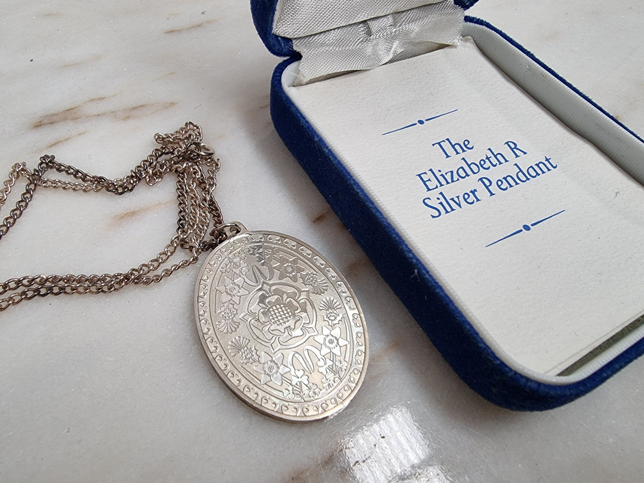 Attractive oval-shaped sterling silver ingot pendant issued by Franklin Mint in 1977 to commemorate Queen Elizabeth II Silver Jubilee. It comes with its original box and paperwork.