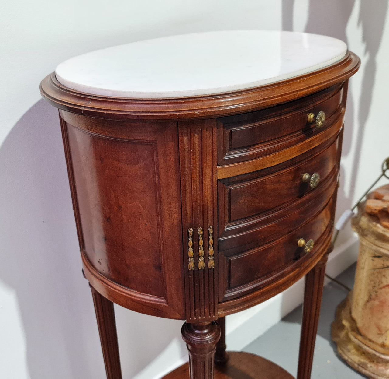 Round Louis XVI style Mahogany marble top side table. It has one drawer and a cupboard for storage. It is in good original detailed condition.
