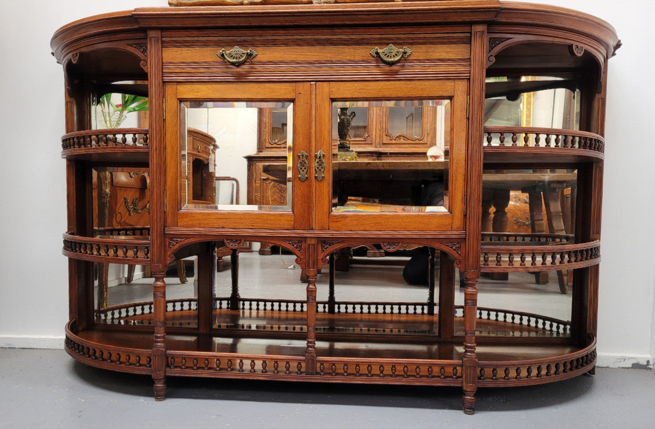 A high quality Antique Walnut sideboard featuring two mirrored doors, two drawers and five open shelf areas with mirror backing. It is in good original detailed condition.