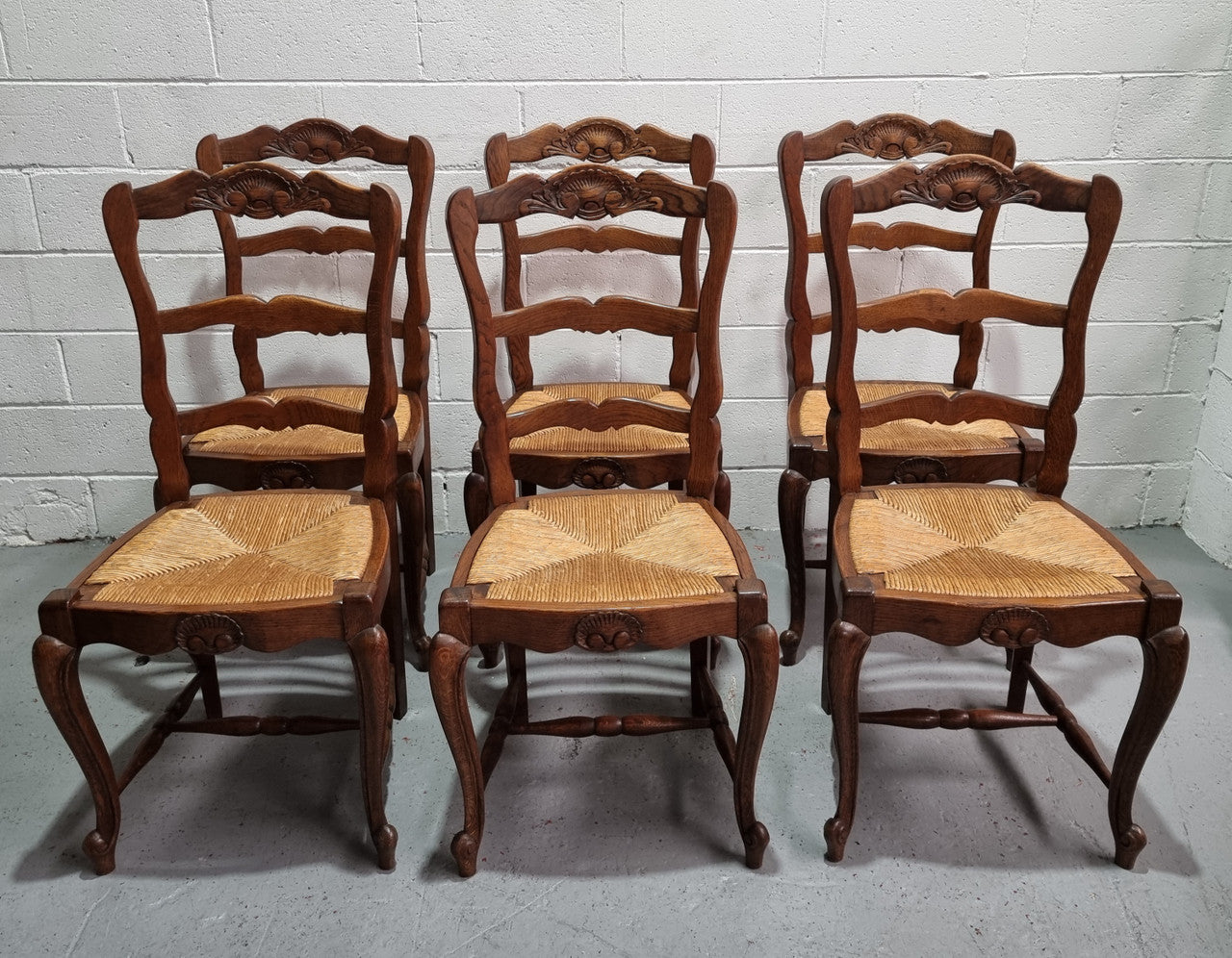 Lovely set of six French oak rush seated provincial dining chairs. They have been sourced from France and are in good detailed condition.