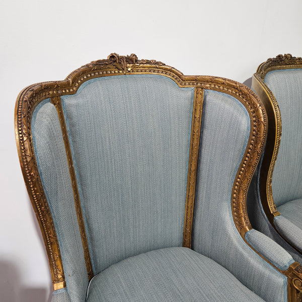 Lovely pair of Louis 16th style gilt & upholstered wingback bergeres with two comfortable cushions. These chairs are in good original condition. Please view photos as they form part of the description.