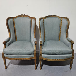 Lovely pair of Louis 16th style gilt & upholstered wingback bergeres with two comfortable cushions. These chairs are in good original condition. Please view photos as they form part of the description.