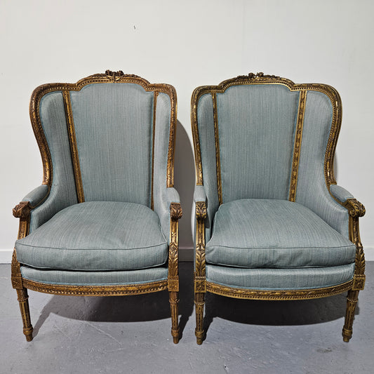 Lovely pair of Louis 16th style gilt & upholstered wingback bergeres with two comfortable cushions. These chairs are in good original condition. Please view photos as they form part of the description.