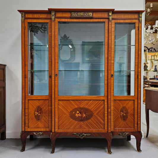 Elegant three door Louis XV transitional style vitrine with decorative bronze mounts. This unit has two glass shelves and one wooden shelf providing plenty of storage. It is in great original detailed condition. Please see the photos as they form part of the description. 