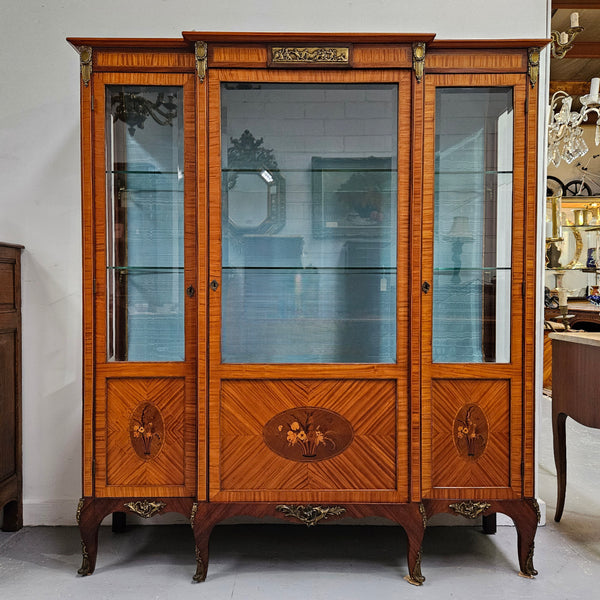 Elegant three door Louis XV transitional style vitrine with decorative bronze mounts. This unit has two glass shelves and one wooden shelf providing plenty of storage. It is in great original detailed condition. Please see the photos as they form part of the description. 