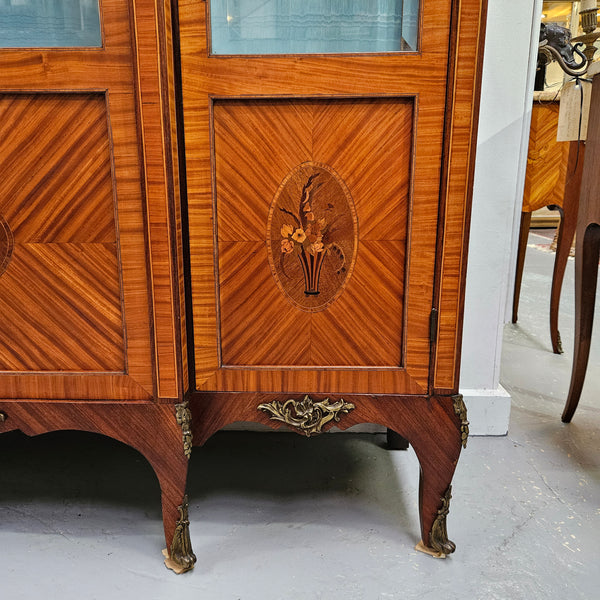 Elegant three door Louis XV transitional style vitrine with decorative bronze mounts. This unit has two glass shelves and one wooden shelf providing plenty of storage. It is in great original detailed condition. Please see the photos as they form part of the description. 