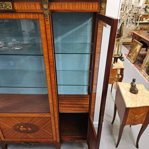Elegant three door Louis XV transitional style vitrine with decorative bronze mounts. This unit has two glass shelves and one wooden shelf providing plenty of storage. It is in great original detailed condition. Please see the photos as they form part of the description. 