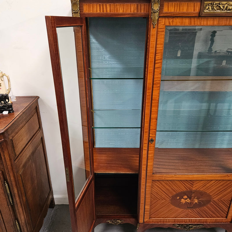 Elegant three door Louis XV transitional style vitrine with decorative bronze mounts. This unit has two glass shelves and one wooden shelf providing plenty of storage. It is in great original detailed condition. Please see the photos as they form part of the description. 