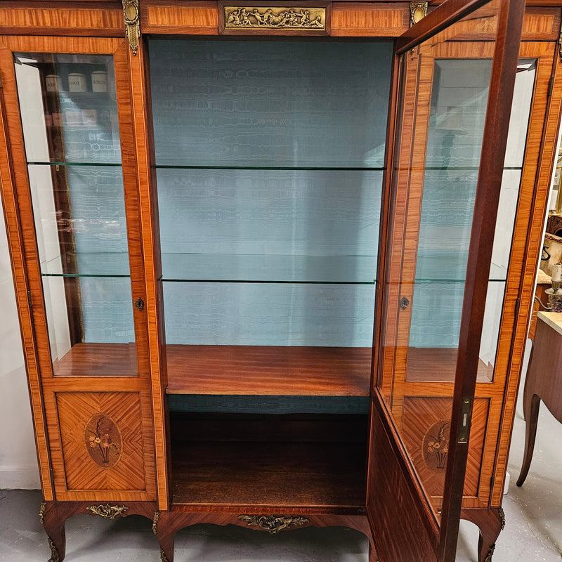 Elegant three door Louis XV transitional style vitrine with decorative bronze mounts. This unit has two glass shelves and one wooden shelf providing plenty of storage. It is in great original detailed condition. Please see the photos as they form part of the description. 