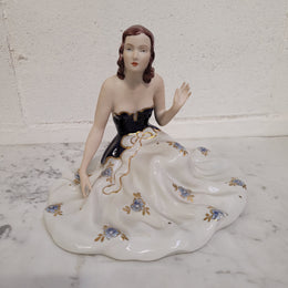 This Royal Dux Bohemia seated figurine of a lady is a beautiful and sophisticated piece. She is wearing a cobalt blue and white dress, and is in good original condition; please review the accompanying photos for more details.