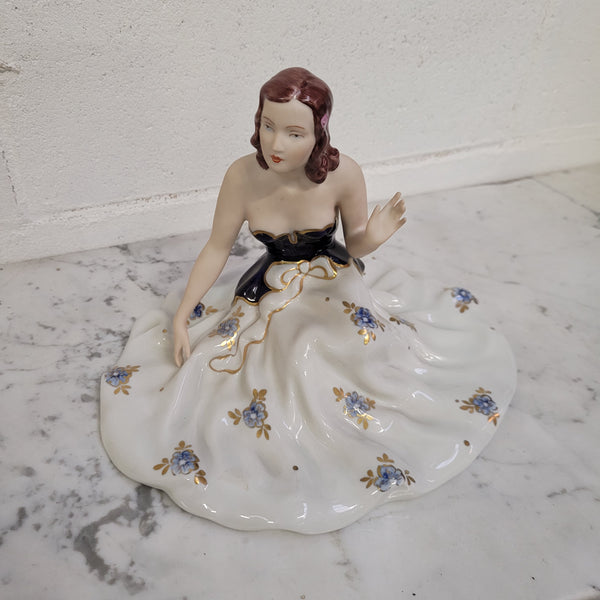 This Royal Dux Bohemia seated figurine of a lady is a beautiful and sophisticated piece. She is wearing a cobalt blue and white dress, and is in good original condition; please review the accompanying photos for more details.