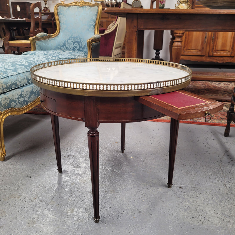 French Louis XVI style Mahogany Bouillotte table, featuring original white Carrara marble top finished nicely with a gilt brass gallery and standing on elegant tapered and fluted legs. It consists of two drawers and two slide-out extensions with leather inserts. Sourced from France and in good original detailed condition. Circa 1930.