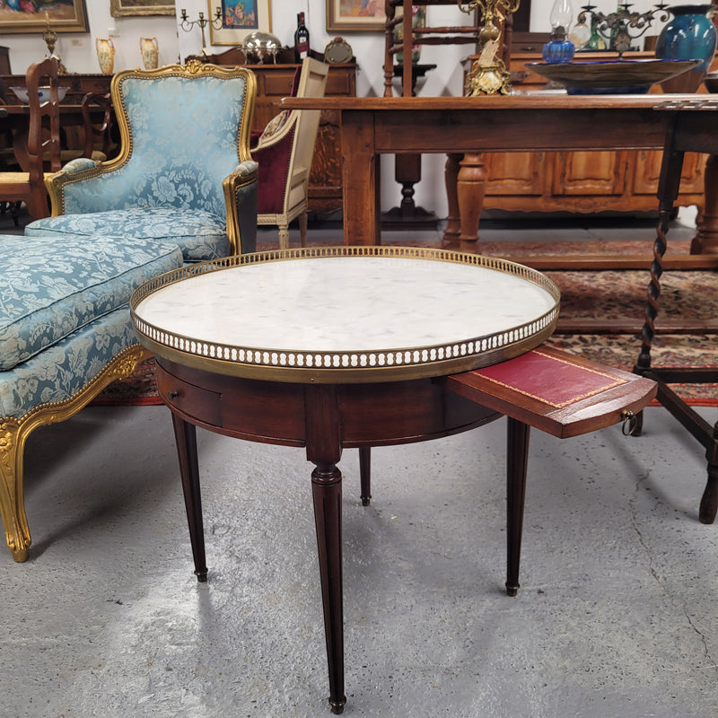 French Louis XVI style Mahogany Bouillotte table, featuring original white Carrara marble top finished nicely with a gilt brass gallery and standing on elegant tapered and fluted legs. It consists of two drawers and two slide-out extensions with leather inserts. Sourced from France and in good original detailed condition. Circa 1930.