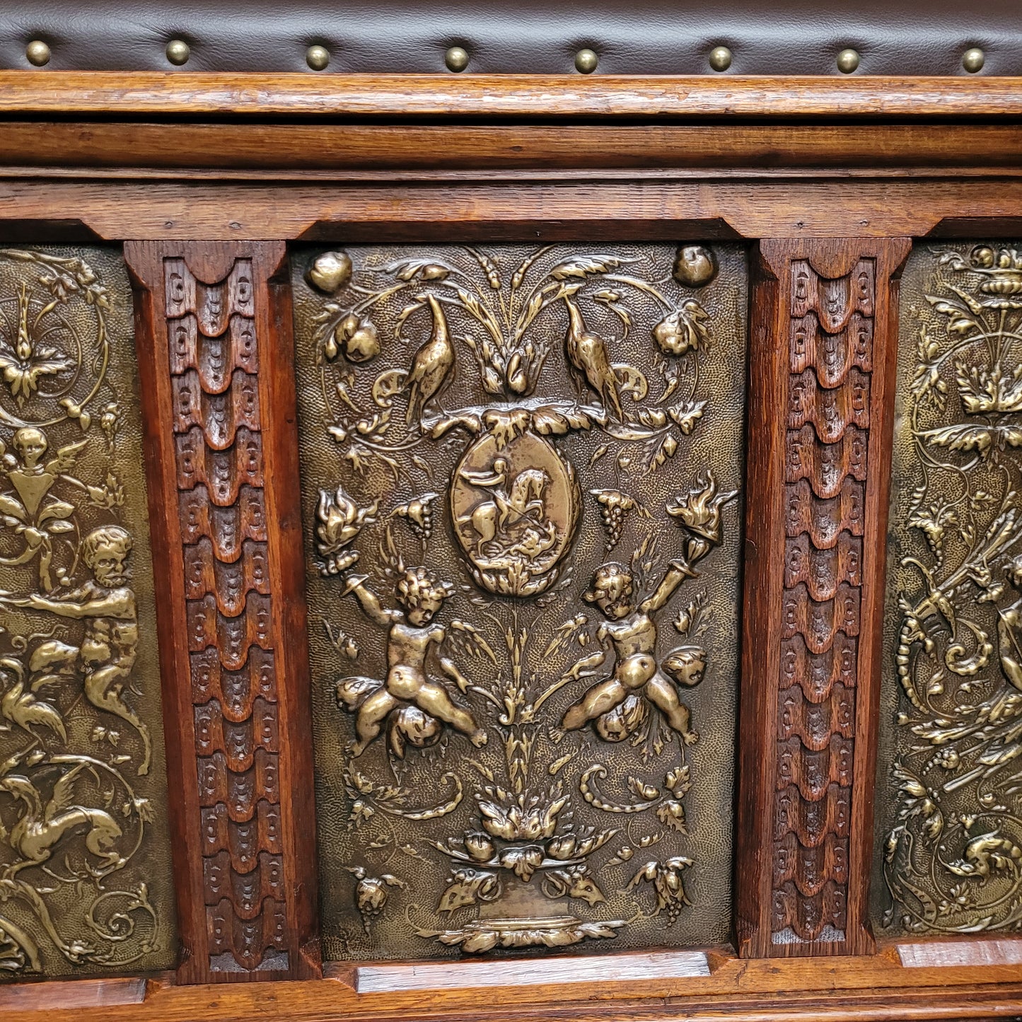 Antique French Oak coffer featuring decorative brass panels and a faux leather top. Brass panels are highly decorative featuring cherubs&nbsp; and faux leather in good used condition with very small signs of wear