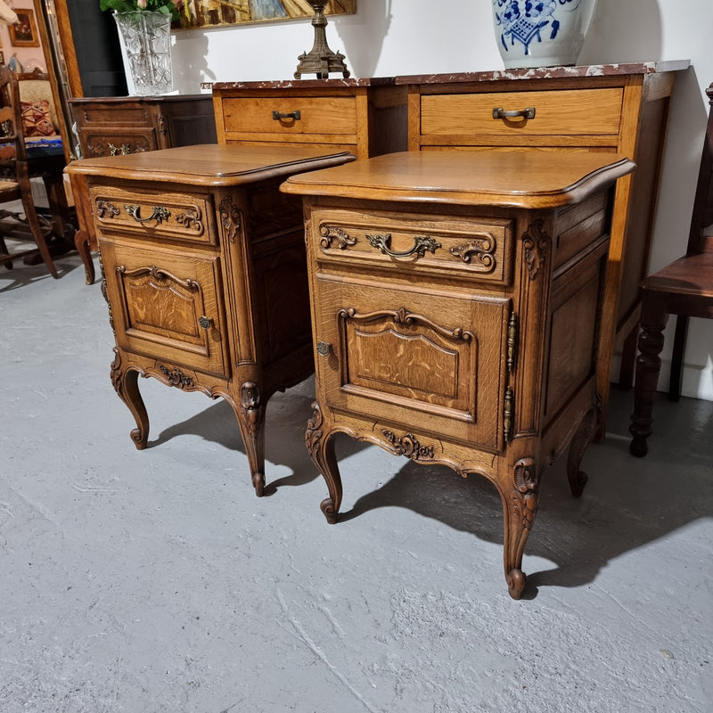 A Rare pair of Antique French Oak Louis XV style wooden top bedside cabinets. Featuring decorative carvings and classical Louis XV cabriole legs. These have been sourced directly from France and are in good original detailed condition.