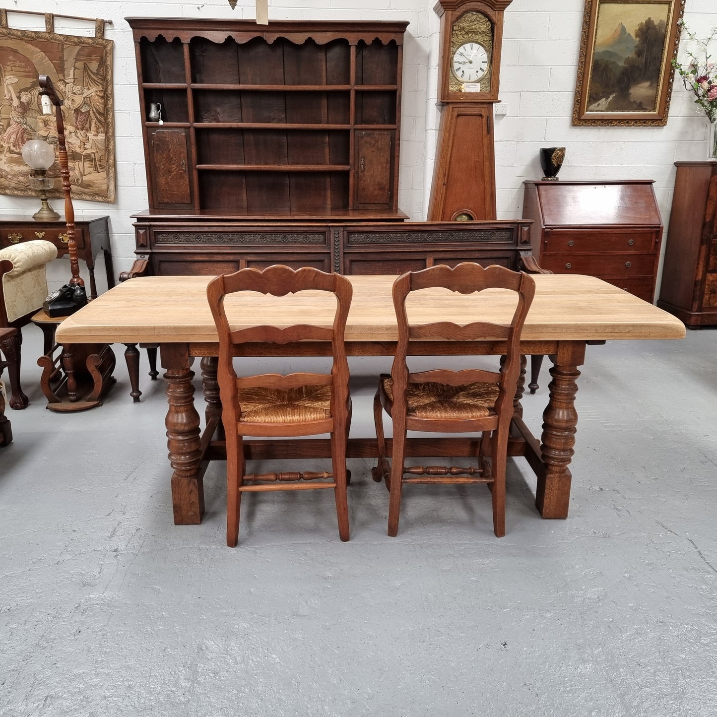 Sourced from France a solid French Oak farmhouse dining table. It features a beautiful stretcher base with turned legs and a raw oak top. The raw oak timber top could be used as is for a distressed look, or finished and waxed for a more refined look. The table very comfortably sits six people and is in good condition.