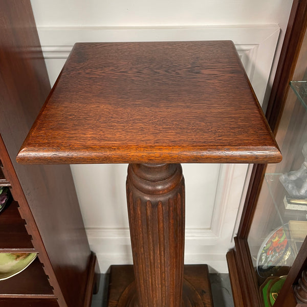 Edwardian oak pedestal with square top and base and featuring a fluted column. In good original condition. 