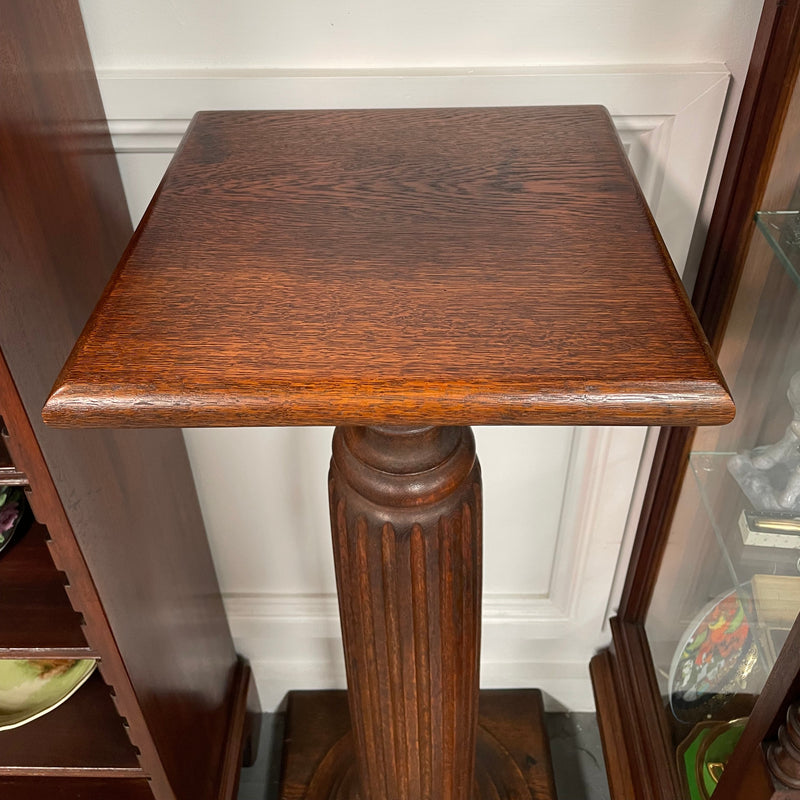 Edwardian oak pedestal with square top and base and featuring a fluted column. In good original condition. 