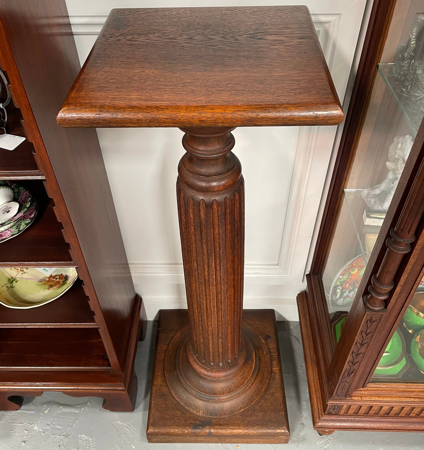 Edwardian oak pedestal with square top and base and featuring a fluted column. In good original condition. 