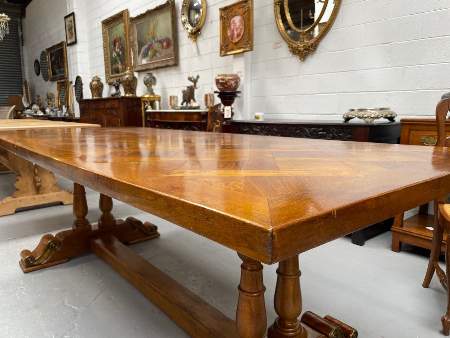 Vintage reclaimed Mahogany parquetry top monastery style dining table. It features beautiful brass mounts on the feet of the table and is in good original detailed condition. It can comfortably seat eight people. 