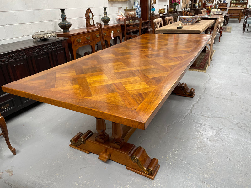 Vintage reclaimed Mahogany parquetry top monastery style dining table. It features beautiful brass mounts on the feet of the table and is in good original detailed condition. It can comfortably seat eight people. 