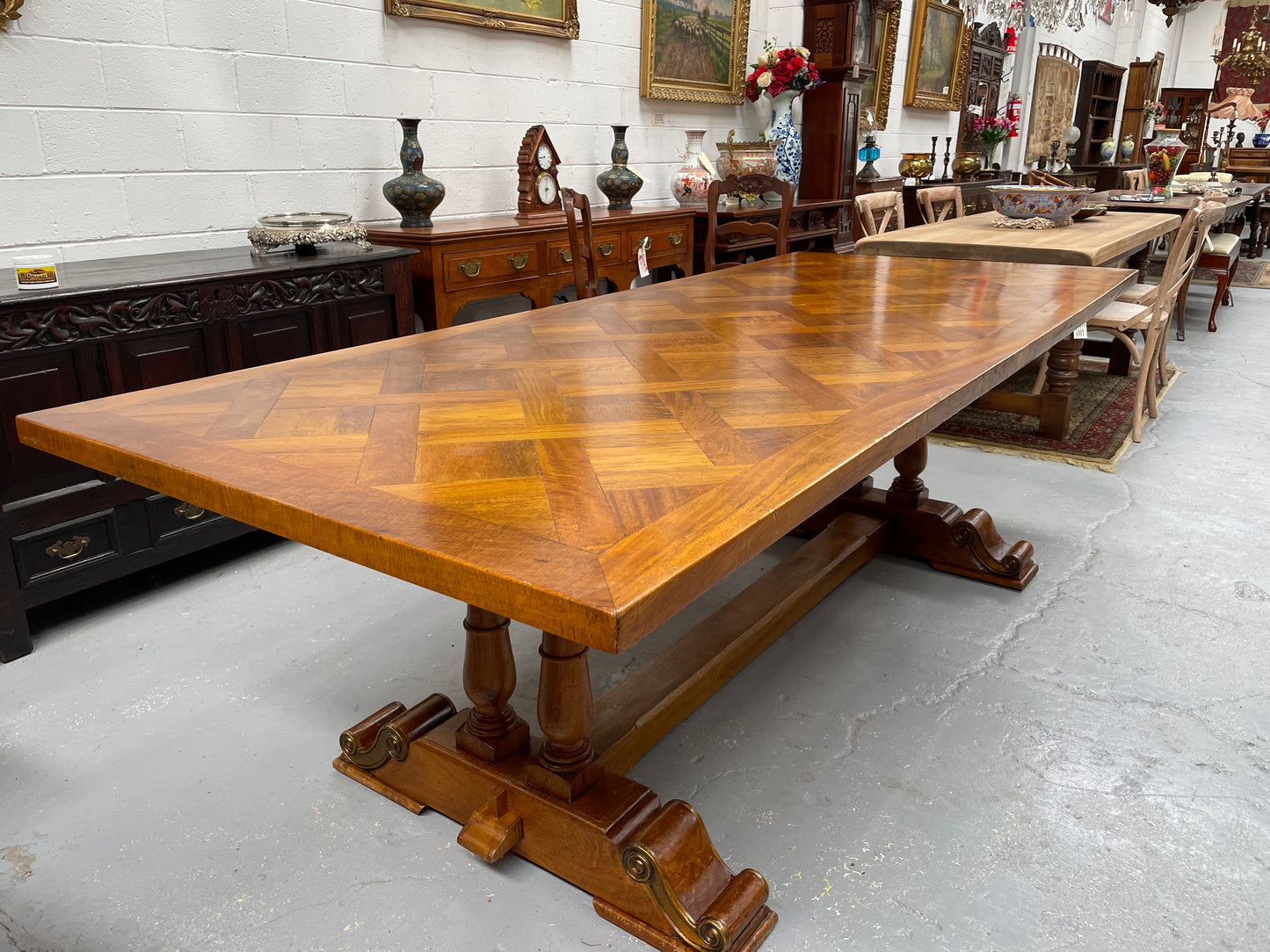 Vintage reclaimed Mahogany parquetry top monastery style dining table. It features beautiful brass mounts on the feet of the table and is in good original detailed condition. It can comfortably seat eight people. 